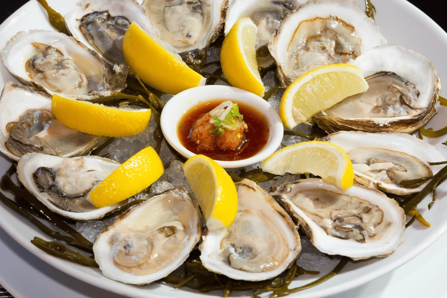 Fresh oysters served on a plate with lemon wedges